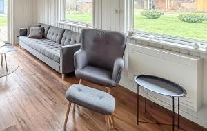 a living room with a couch and a chair at Cozy Home In Sydals With Sauna in Skovby +13 photos
