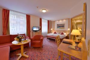 Habitación de hotel con cama y sala de estar. en Ringhotel Weißer Hirsch, en Wernigerode