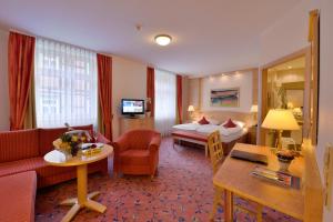 ヴェルニゲローデにあるリングホテル ヴァイサー ヒルシュのベッドとリビングルームが備わるホテルルームです。