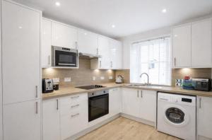 a kitchen with white cabinets and a washer and dryer at Taigh Oisean 4 Birnam Place Pitlochry in Pitlochry