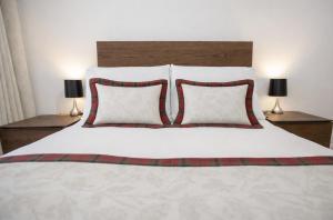 a white bed with two red pillows and two lamps at Taigh Oisean 4 Birnam Place Pitlochry in Pitlochry