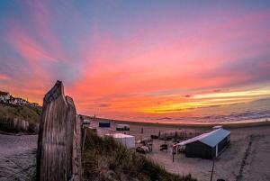 a sunset on a beach with a building on the sand at Studio At C in Zandvoort