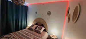 a bedroom with a bed in a room with a neon light at Agréable T2 Classé 3 étoiles, refait à neuf, dans quartier calme in Rodez