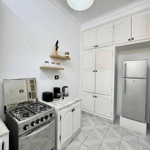 a white kitchen with a stove and a refrigerator at Maison Azur la Marsa plage in Tunis