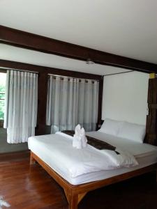 a bedroom with a large white bed with a bow on it at Monkeaw in Mae On