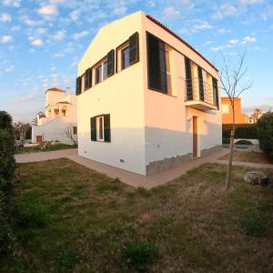 a white house with black windows on a yard at Villa Tord Massot 11 in Ciutadella