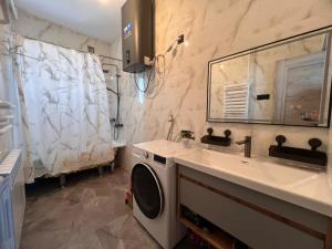 a bathroom with a sink and a washing machine at Taldy-Suu Guesthouse in Taldysu