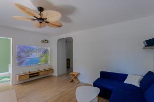 a living room with a blue couch and a ceiling fan at Le Clos de Vallaurias in Vallauris