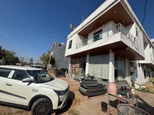 a white suv parked in front of a house at Hotel Laxmi Palace in Khātu