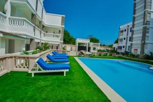 a pool with blue lounge chairs next to a building at Diani Dream stays in Diani Beach +10 photos