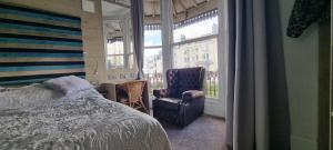 a bedroom with a bed and a chair and a window at Marine View in Brighton & Hove