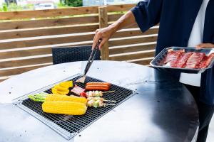 a person is grilling vegetables on a grill at Villa Hello Fujisan ヴィラハローフジサン 屋根付きBBQ場 ワンちゃん大歓迎 A220 in Fujiyoshida