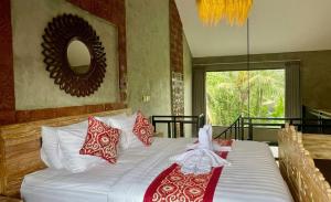 a bedroom with a large bed with red and white pillows at Juminten Villa in Ubud +14 photos