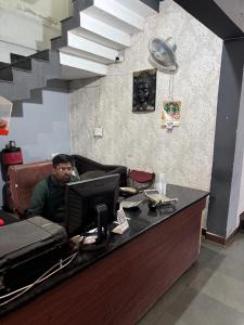 a man sitting at a desk with a computer at hotel apni haveli in Mandsaur +13 photos