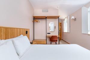 a bedroom with a white bed and a chair at Cascais Hotel in Cascais