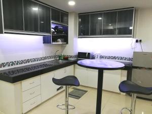a kitchen with a table and two stools at NF Suites D'Perdana Condo in Kota Bharu