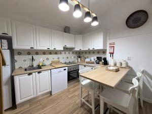 a kitchen with white cabinets and a wooden table at Casa do Serro de Lá in Santa Clara-a-Nova