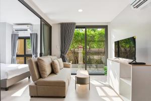a bedroom with a couch and a bed and a tv at Tiva Residence Bangkok in Bangkok