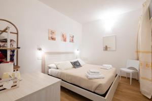a white bedroom with a bed with towels on it at Stentadì Guest House Tortolì in Tortolì