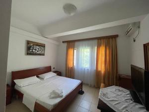 a bedroom with a bed and a television and a window at Bar-Restaurant-Hotel River in Këlcyrë Fshat