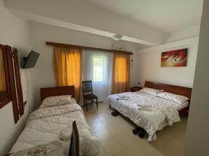 a bedroom with two beds and a chair and a window at Bar-Restaurant-Hotel River in Këlcyrë Fshat