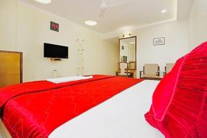 a large red bed in a white room with a tv at Hotel Sarita - Near Surat Railway Station in Surat