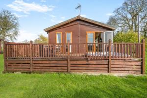 a small cabin with a wooden fence in the grass at Field View 1 bed-No Pets-Cedar in Eye