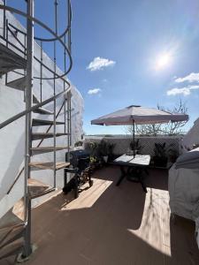 a patio with a grill and a table and an umbrella at Casa do Serro de Lá in Santa Clara-a-Nova