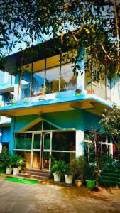 a blue and white building with potted plants in front of it at MONIRAMS INN. in Kāziranga