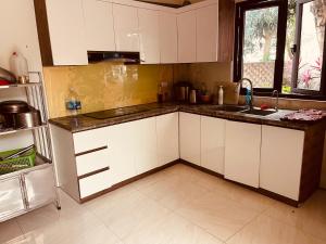a kitchen with white cabinets and a sink at Villa KimAnh in Sóc Sơn