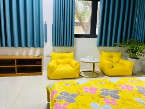 a room with two yellow chairs and a bed at Villa KimAnh in Sóc Sơn