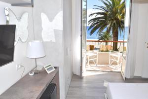 a room with a bed and a television and a balcony at Hotel Boncardo in Finale Ligure