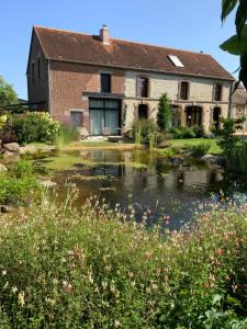 an old house with a pond in front of it at La Grange des Loges in Boucé