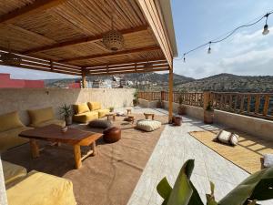 a patio with a couch and tables on a balcony at Manapany Surf Camp in Tamraght Ouzdar