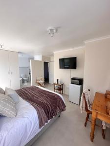 a bedroom with a bed and a table and a television at 95 on Acacia in Helderberg