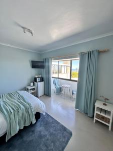 a bedroom with a bed and a large window at 95 on Acacia in Helderberg +8 photos