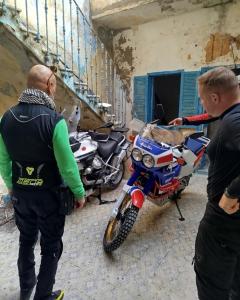 two men looking at a motorcycle parked in a building at Al Madina, traditional Riad in Bizerte