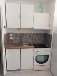 a kitchen with white cabinets and a sink and a stove at Le goéland in Port Leucate +6 photos