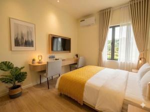 a bedroom with a bed and a desk with a computer at OnsenHouse Boutique Stay - Căn hộ gần biển Mỹ Khê in Danang