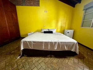 a bedroom with a large bed in a yellow wall at Mega Suíte Na Melhor Localização in Botucatu