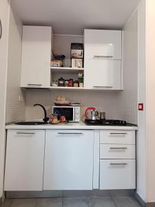 a white kitchen with white cabinets and a microwave at Adriatic Room 50 m dalla stazione Ferroviaria di Ciampino e dalla navetta aeroportuale in Ciampino