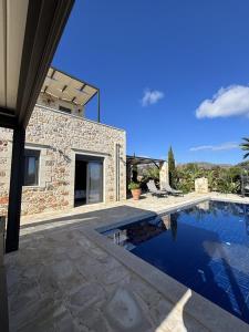 a swimming pool in front of a stone house at MayaElisa Villa with Heated Pool, By Hellocrete in Vamos