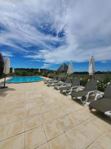 a row of chairs and umbrellas next to a pool at Les Cabanes de Rouffignac in Rouffignac Saint-Cernin