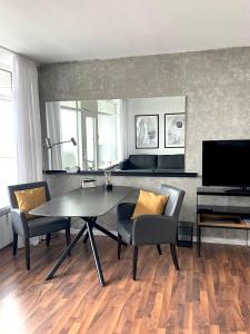 a living room with a table and chairs and a television at Traumblick auf‘s Meer in Sierksdorf