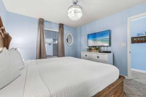 a bedroom with a white bed and a tv at Pelican Beach Resort 504 in Destin