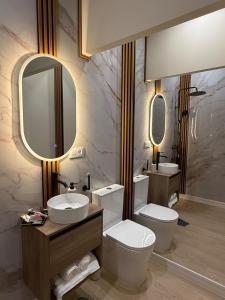 a bathroom with a toilet and a sink and mirrors at Bianca Suites III in Bormujos +1 photo