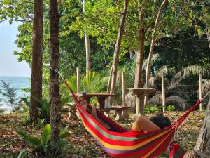 a person laying in a hammock on the beach at Mutodon Green in Kuala Penyu
