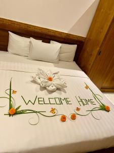a bed with a welcome sign on it with flowers on it at Dava Guest House Gianyar in Gianyar