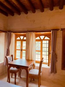 a dining room with a table and chairs and windows at Yusuf Çavuş Konağı in Halfeti