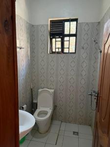 a bathroom with a toilet and a sink and a window at Eden house in Kigali +12 photos